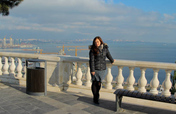 Traveling smile girl with a backpack in Baku, Azerbaijan. Girl walks around the Martyrs Lane viewpoint. Panorama on the Baku Boulevard and Caspian Sea baku national park stock pictures, royalty-free photos & images