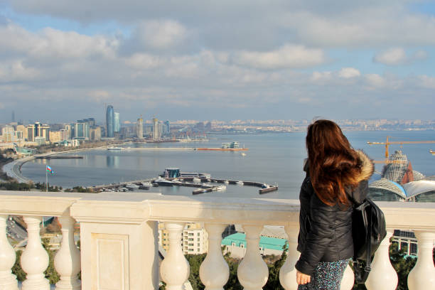 Traveling girl with a backpack in Baku, Azerbaijan. Girl walks around the Martyrs Lane viewpoint. Panorama on the Baku Boulevard baku national park stock pictures, royalty-free photos & images