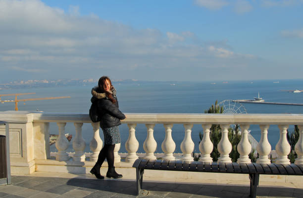 Traveling smile girl with a backpack in Baku, Azerbaijan. Girl walks around the Martyrs Lane viewpoint. Panorama on the Baku Boulevard and Caspian Sea baku national park stock pictures, royalty-free photos & images