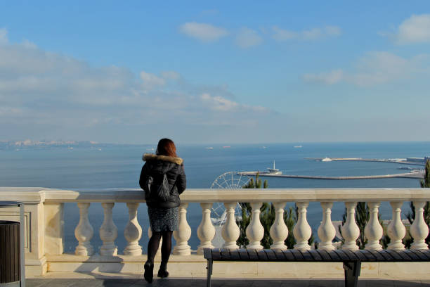 Traveling girl with a backpack in Baku, Azerbaijan. Girl walks around the Martyrs Lane viewpoint. Panorama on the Baku Boulevard and Caspian Sea baku national park stock pictures, royalty-free photos & images