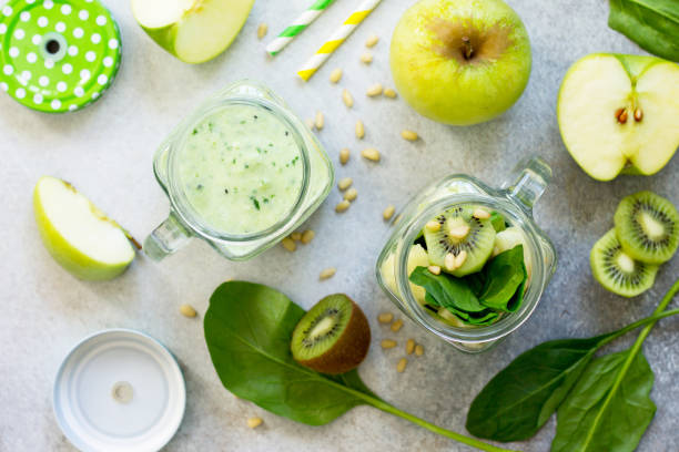 istock Green smoothies and apple, kiwi, spinach, pine nuts. Proper nutrition. Top view flat lay background. 930549708