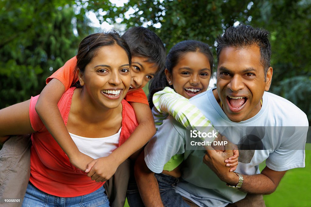 Indian casal dando levando para crianças em um parque. - Foto de stock de Brincar royalty-free