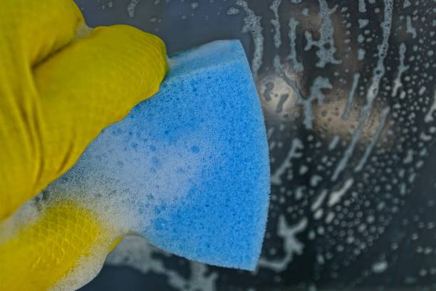 istock A hand in a yellow glove washes a blue sponge window 930568016