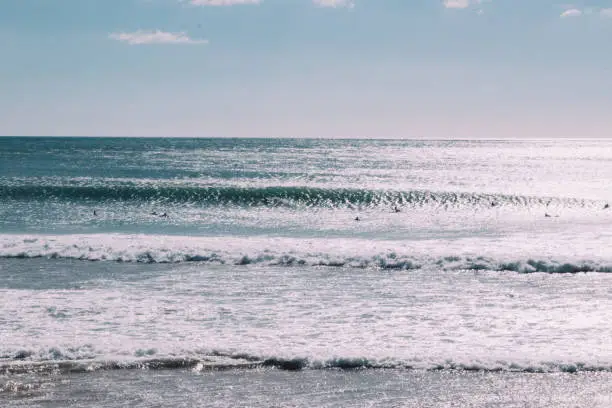 Photo of Surfers in the ocean on a sunny day with sun glare on ocean surface