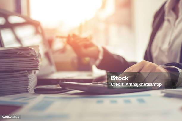 Business Woman Using Calculator And Writing Make Note With Calculate Woman Working At Office With Laptop And Documents On His Desk Stock Photo - Download Image Now