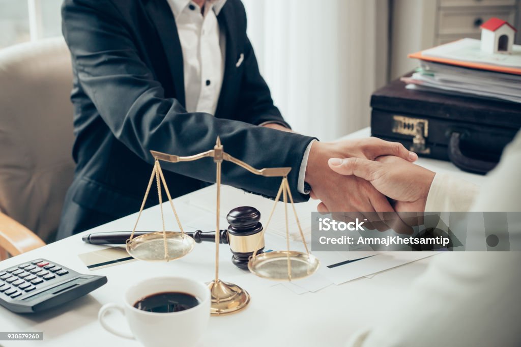 Uomo d'affari che stringe la mano per sigillare un accordo con i suoi avvocati partner o avvocati che discutono di un accordo contrattuale - Foto stock royalty-free di Avvocato