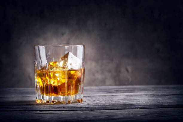 Faceted glass of whiskey with ice stock photo