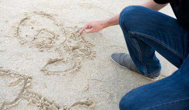 istock A guy in jeans draws a finger on the sand 930591480