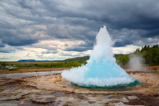 Famous Strokkur fountain geyser hot blue water eruption with cloud sky and surrounding Icelandic landscape, Iceland Famous Strokkur fountain geyser hot blue water eruption with cloud sky and surrounding Icelandic landscape, Iceland fumarole photos stock pictures, royalty-free photos & images