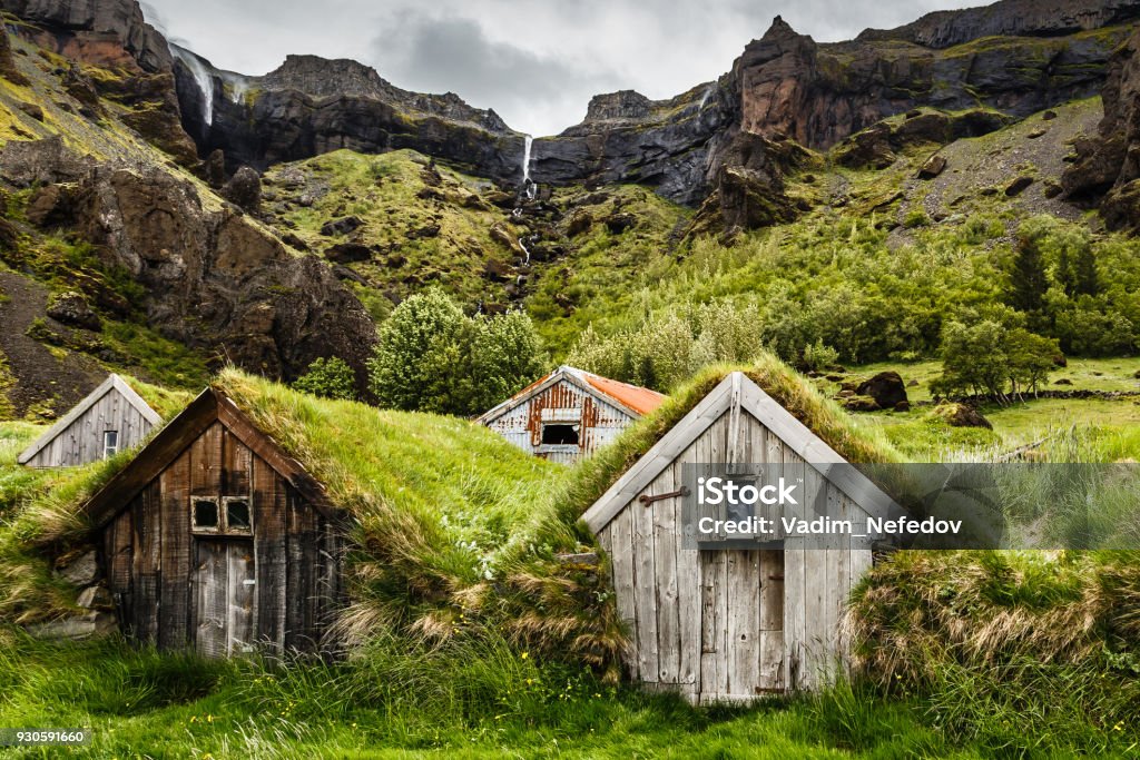 Icelandic turf houses and rocky canyon with waterfall in the background near Kalfafell vilage, South Iceland Icelandic turf houses and rocky canyon with waterfall in the background near Kalfafell village, South Iceland Iceland Stock Photo