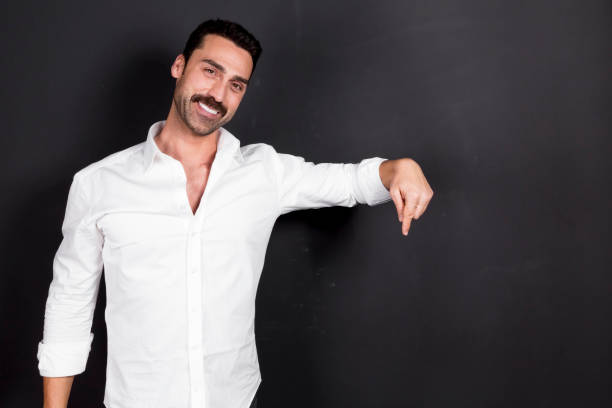 Young handsome man with beard and mustache studio portrait Young handsome man with beard and mustache showing direction for copy space, studio portrait man hand down stock pictures, royalty-free photos & images