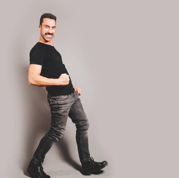Man with moustache posing a happy facial expression, studio portrait against black background