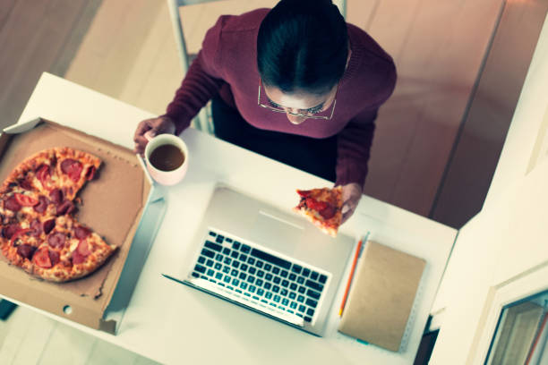 istock Top view of young woman eating pizza while working 930604874