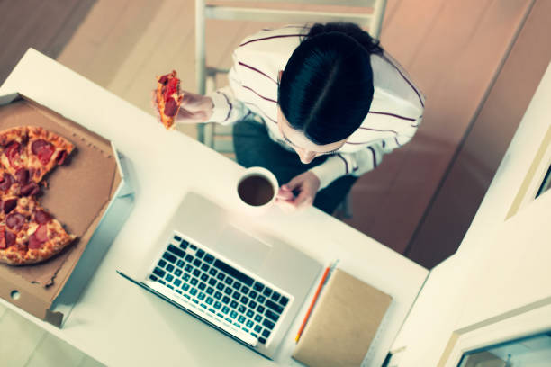 istock Top view of young woman enjoying pizza at work 930604908