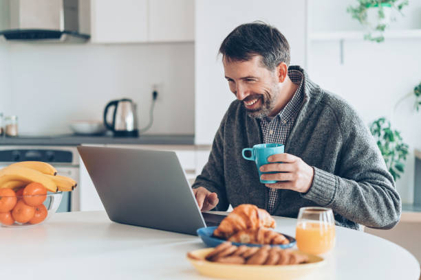 istock Middle aged man with laptop in the kitchen 930607758
