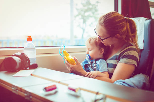 Happy mother and her baby boy travelling in train in summer