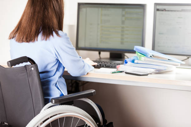 オフィス デスクのコンピューターの作業女性障害者シーティング車椅子 - working people physical impairment wheelchair ストックフォトと画像