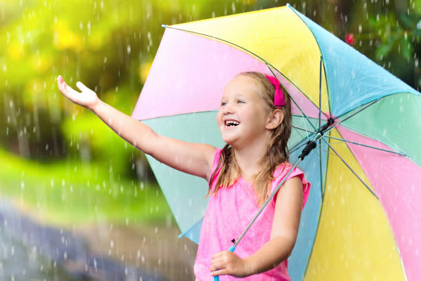 istock Kid with umbrella playing in summer rain. 930612366
