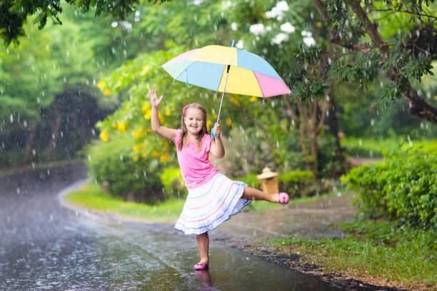 istock Kid with umbrella playing in summer rain. 930612568