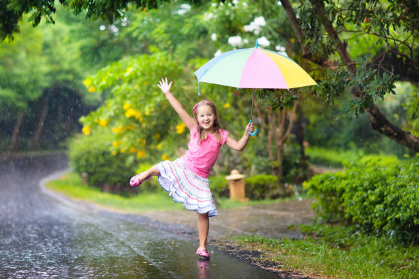 kid with umbrella playing in summer rain. - rainbow umbrella descriptive color multi colored imagens e fotografias de stock