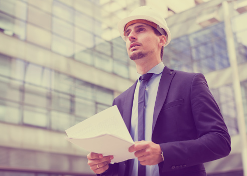 Professional man in jacket and helmet working with documents