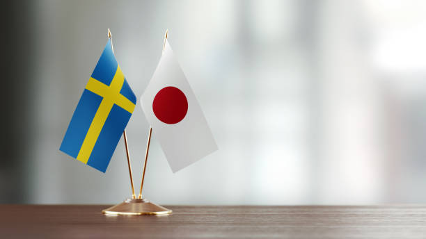 istock Swedish And Japanese Flag Pair On A Desk Over Defocused Background 930658384
