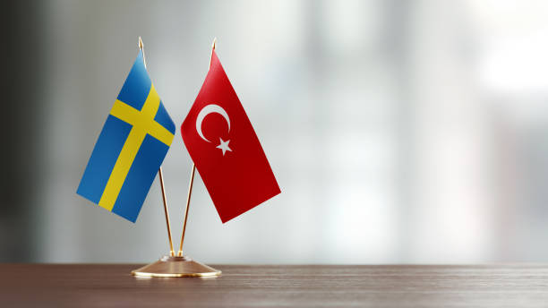 Swedish And Turkish Flag Pair On A Desk Over Defocused Background Swedish and Turkish flag pair on desk over defocused background. Horizontal composition with copy space and selective focus. sweden flag stock pictures, royalty-free photos & images
