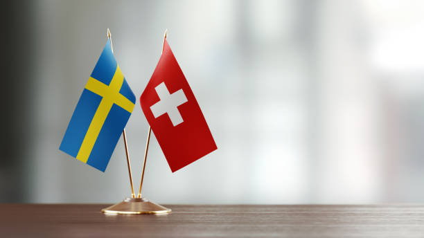 istock Swedish And Swiss Flag Pair On A Desk Over Defocused Background 930661476