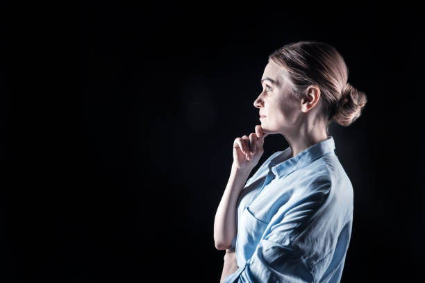 Beautiful woman. Happy nice thoughtful woman standing half face an holding her chin while looking in front of her