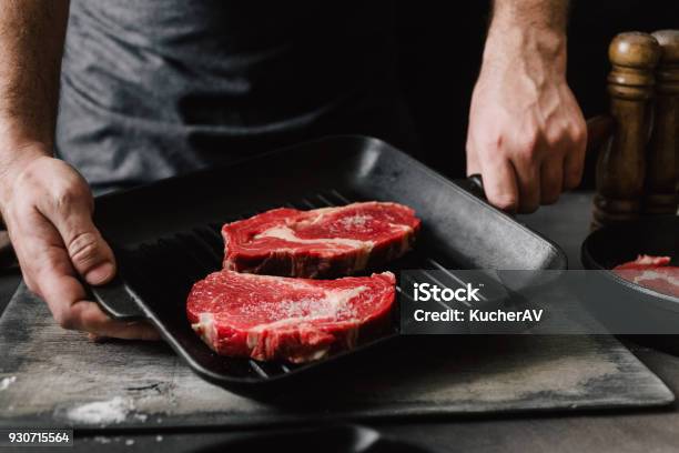 Foto de Homem Machos Mãos Segurando Uma Panela De Grelhar Com Bifes Na Cozinha A Cozinhar Bifes e mais fotos de stock de Carne