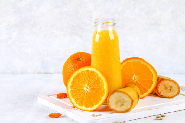 istock Orange smoothies from orange, banana on a gray concrete table. 930716018