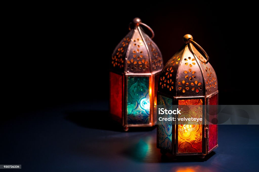 Duas lanternas orientais coloridas de lâmpada queimam com velas com reflexão de cor em fundo preto escuro para o Ramadã e outros feriados muçulmanos islâmicos - Foto de stock de Ramadã royalty-free