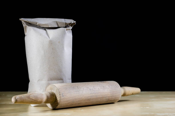 Flour and rolling pin for kneading the dough on the kitchen table. Accessories and kitchen products. Black table top.