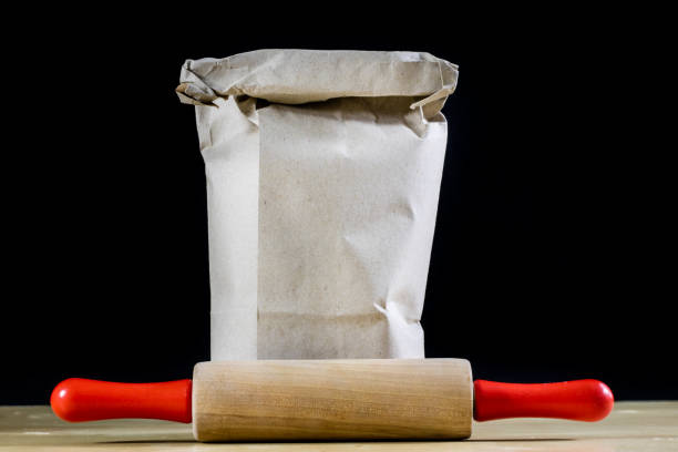 Flour and rolling pin for kneading the dough on the kitchen table. Accessories and kitchen products. Black table top.