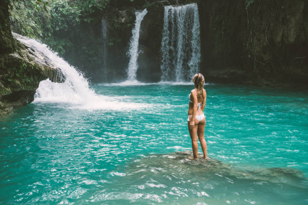 istock Young woman contemplating beautiful waterfall 930733502