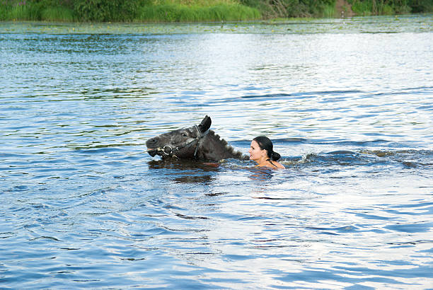 istock woman swimming winth  stallion in river 93073983