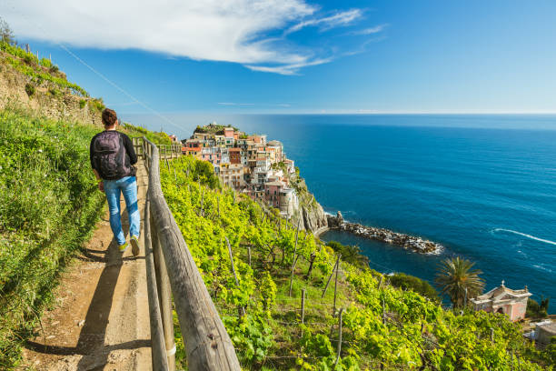 mujer de senderismo en el camino en viña cerca de pueblo de manarola. cinque terre. liguria, italia. - liguria fotografías e imágenes de stock