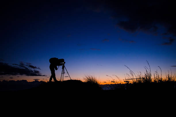 Male photographer taking picture with  camera at sunset time
