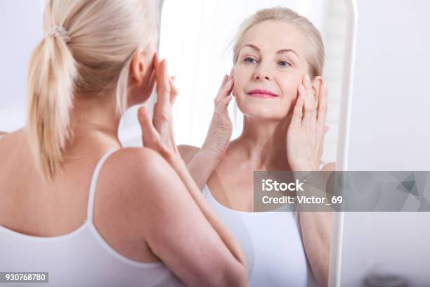 Middle Aged Woman Looking At Wrinkles In Mirror Plastic Surgery And Collagen Injections Makeup Macro Face Selective Focus Stock Photo - Download Image Now