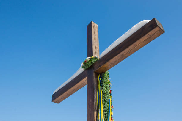 wooden christian cross with ukrainian flag color ribbons, yellow and blue, on the plain blue sky background, concept of hope, freedom, rebellion, nationalism, patriotism. - cross cross shape christianity hope imagens e fotografias de stock