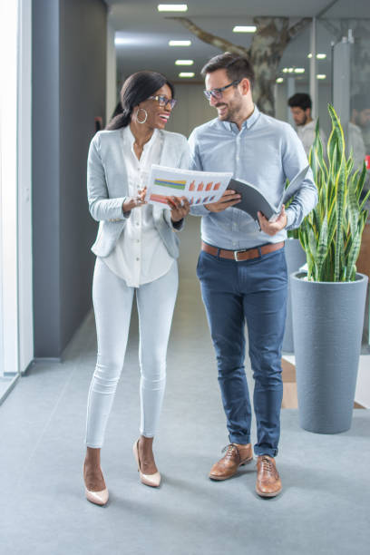 istock Happy business people working together with document while walking through office hallway. 930775784