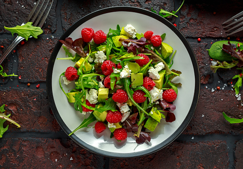 Fresh Tasty Raspberry salad with avocado, green vegetables, nuts, feta cheese, olive oil and herbs. healthy food