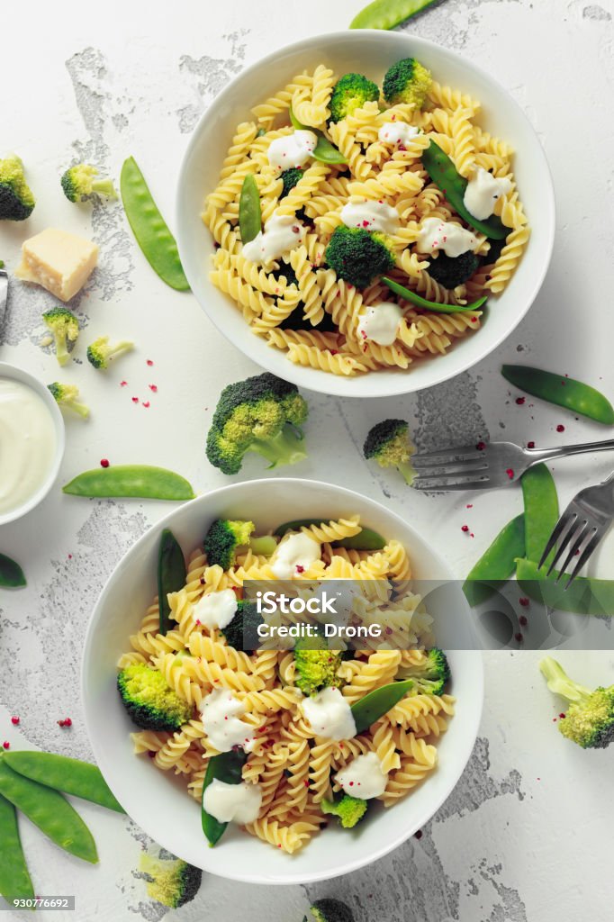 Pasta with green vegetables broccoli, Mange tout and creamy sauce in white plate Pasta with green vegetables broccoli, Mange tout and creamy sauce in white plate. Salad Dressing Stock Photo