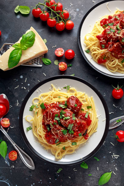 boulettes de pâtes spaghetti avec sauce tomate, basilic, fromage parmesan herbes sur fond foncé - macaroni photos et images de collection