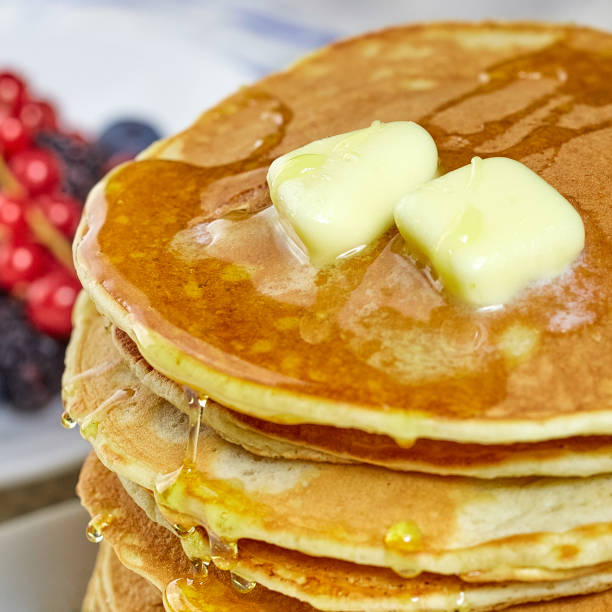 stack of pancakes with honey and butter. Shot large. In the background berries. stock photo
