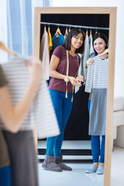istock Cheerful tailor demonstrating a new dress to her visitor 930781648