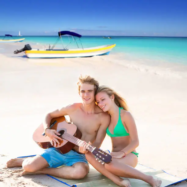 Blond young tourist couple playing guitar at beach in Mexico Caribbean photo mount
