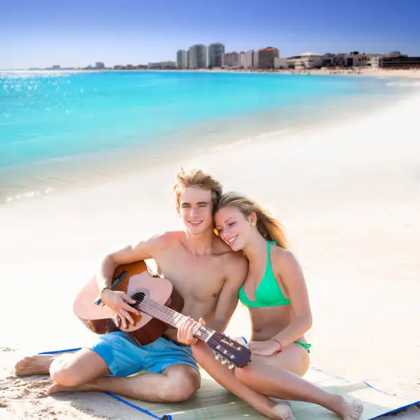 Blond young tourist couple playing guitar at beach in Mexico Caribbean photo mount