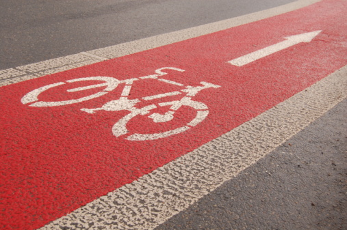 Bicycle lane sign on red asphalt road.