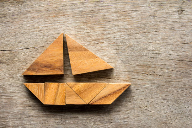 Tangram puzzle in sail boat shape on wooden background